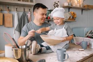 joven hombre y su hijo con horno sábana en cocina. padre con pequeño hijo en el cocina. foto