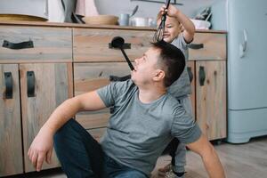 Young man and his son with oven sheet in kitchen. Father with little son on the kitchen photo