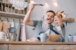 joven hombre y su hijo con horno sábana en cocina. padre con pequeño hijo en el cocina. foto