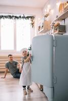 Young man and his son with oven sheet in kitchen. Father with little son on the kitchen. photo