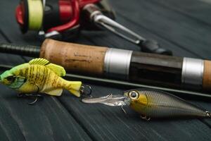 Fishing tackle - fishing spinning, hooks and lures on darken wooden background. Top view photo