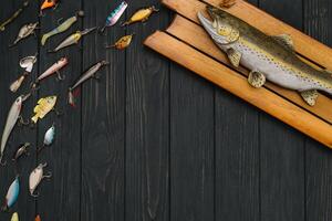 Fishing tackle - fishing spinning, hooks and lures on darken wooden background. Top view photo