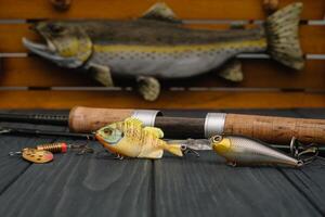 Fishing tackle - fishing spinning, hooks and lures on darken wooden background. Top view photo