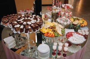 postres con frutas, mousse, galletas. diferente tipos de dulce pasteles, pequeño vistoso dulce pasteles, macarrón, y otro postres en el dulce bufé. caramelo bar para cumpleaños. foto