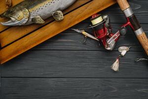 pescar entrada - pescar hilado, manos y señuelos en oscurecer de madera antecedentes. parte superior vista. foto