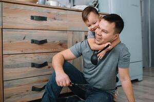 Young man and his son with oven sheet in kitchen. Father with little son on the kitchen photo