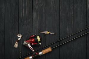 Fishing tackle - fishing spinning, hooks and lures on darken wooden background. Top view photo