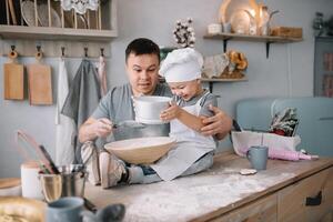 joven hombre y su hijo con horno sábana en cocina. padre con pequeño hijo en el cocina. foto