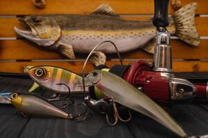 Fishing tackle - fishing spinning, hooks and lures on darken wooden background. Top view photo