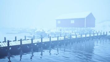 nebbioso giorno. bacino con Casa su vecchio di legno molo nel il norvegese mare video