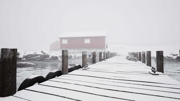 schneebedeckt Seebrücke mit rot Gebäude im norwegisch Meer video