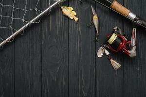 Fishing tackle - fishing spinning, hooks and lures on darken wooden background. Top view photo