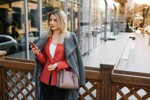 Young fashionable business woman in hurry on city street, talking on mobile phone photo