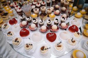 desserts with fruits, mousse, biscuits. Different types of sweet pastries, small colorful sweet cakes, macaron, and other desserts in the sweet buffet. candy bar for birthday. photo