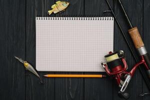 Fishing tackle - fishing spinning, hooks and lures on darken wooden background. Top view photo