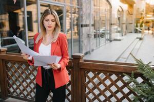 Portrait of business women in feeling of concentrate stress and see stand and hold the paper file sheet in the outdoor pedestrian walk way with the city space of exterior modern facade building photo