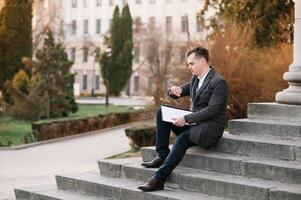 Handsome man in suit is looking at his watch attentively. He is waiting for his business partner. Look Exquisitely Stylish. photo