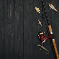 Fishing tackle - fishing spinning, hooks and lures on darken wooden background. Top view photo
