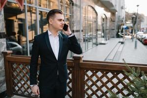 joven negocio hombre con un teléfono inteligente cerca de moderno edificio. foto