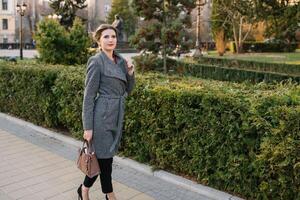 retrato de negocio mujer en sensación de concentrado estrés y ver estar y sostener el papel archivo sábana en el al aire libre peatonal caminar camino con el ciudad espacio de exterior moderno fachada edificio foto