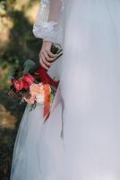 Bride stands in a white wedding dress with a bouquet of flowers photo