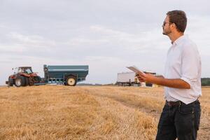 Happy farmer standing in a wheat field after the harvest. Agriculture concept. photo