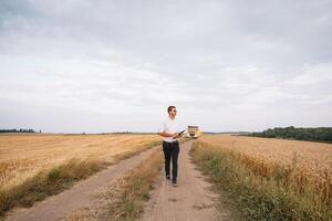 young farmer engineer standing on wheat field. photo