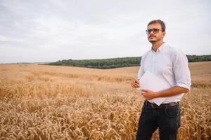 joven granjero ingeniero en pie en trigo campo. foto