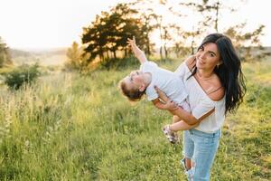 elegante madre y hermoso hija teniendo divertido en el naturaleza. contento familia concepto. belleza naturaleza escena con familia al aire libre estilo de vida. familia descansando juntos. felicidad en familia vida. madres día. foto