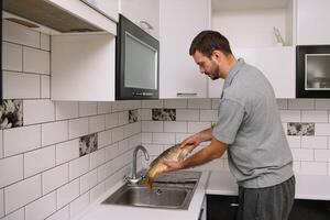 Man cutting fresh fish in kitchen in home. Man butchering fish for cook. photo