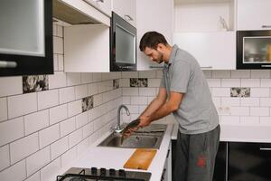 Man cutting fresh fish in kitchen in home. Man butchering fish for cook. photo