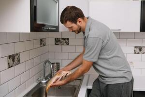 Man cutting fresh fish in kitchen in home. Man butchering fish for cook. photo