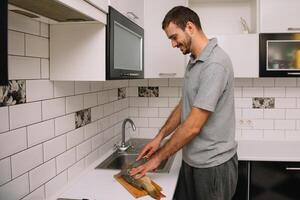 Man cutting fresh fish in kitchen in home. Man butchering fish for cook. photo