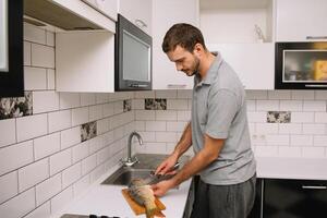 Man cutting fresh fish in kitchen in home. Man butchering fish for cook. photo