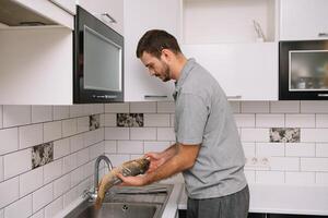 hombre corte Fresco pescado en cocina en hogar. hombre matanza pescado para cocinar. foto