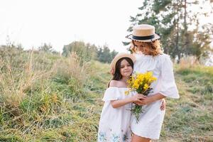 elegante madre y hermoso hija teniendo divertido en el naturaleza. contento familia concepto. belleza naturaleza escena con familia al aire libre estilo de vida. familia descansando juntos. felicidad en familia vida. madres día. foto