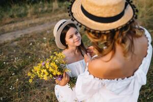 elegante madre y hermoso hija teniendo divertido en el naturaleza. contento familia concepto. belleza naturaleza escena con familia al aire libre estilo de vida. familia descansando juntos. felicidad en familia vida. madres día. foto