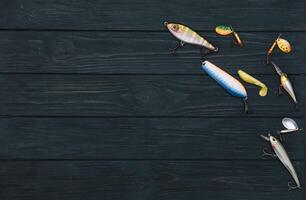 Fishing tackle - fishing spinning, hooks and lures on darken wooden background. Top view photo