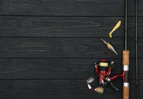 Fishing tackle - fishing spinning, hooks and lures on darken wooden background. Top view. photo