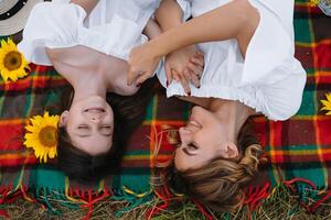 Top view of happy woman smiling and playing with her cute little child, lying outdoor.Loving mother and daughter spend time together in a park. Mom and kid has fun. Mother's day photo