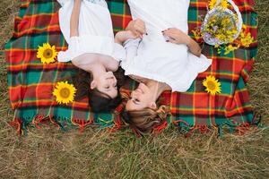 Top view of happy woman smiling and playing with her cute little child, lying outdoor.Loving mother and daughter spend time together in a park. Mom and kid has fun. Mother's day photo