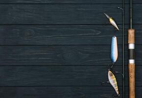 Fishing tackle - fishing spinning, hooks and lures on darken wooden background. Top view photo