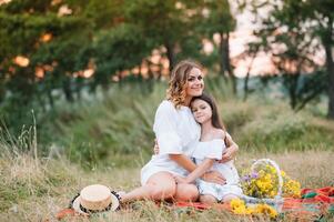 elegante madre y hermoso hija teniendo divertido en el naturaleza. contento familia concepto. belleza naturaleza escena con familia al aire libre estilo de vida. familia descansando juntos. felicidad en familia vida. madres día. foto