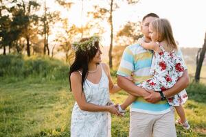 Happy family of three persons walking the grass in the park. photo