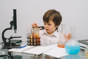 The boy with a microscope and various colorful flasks on a white background. A boy doing experiments in the laboratory. Explosion in the laboratory. Science and education photo
