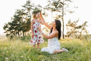 elegante madre y hermoso hija teniendo divertido en el naturaleza. contento familia concepto. belleza naturaleza escena con familia al aire libre estilo de vida. familia descansando juntos. felicidad en familia vida. madres día. foto