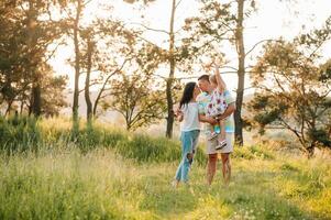 Happy family of three persons walking the grass in the park. photo