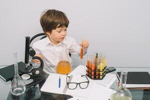 The boy with a microscope and various colorful flasks on a white background. A boy doing experiments in the laboratory. Explosion in the laboratory. Science and education photo