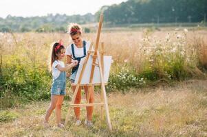 Young mother and her daughter have fun, mother's Day. smiling mother with beautiful daughter draws nature. photo