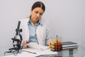 A beautiful female medical or scientific researcher using her microscope in a laboratory. photo